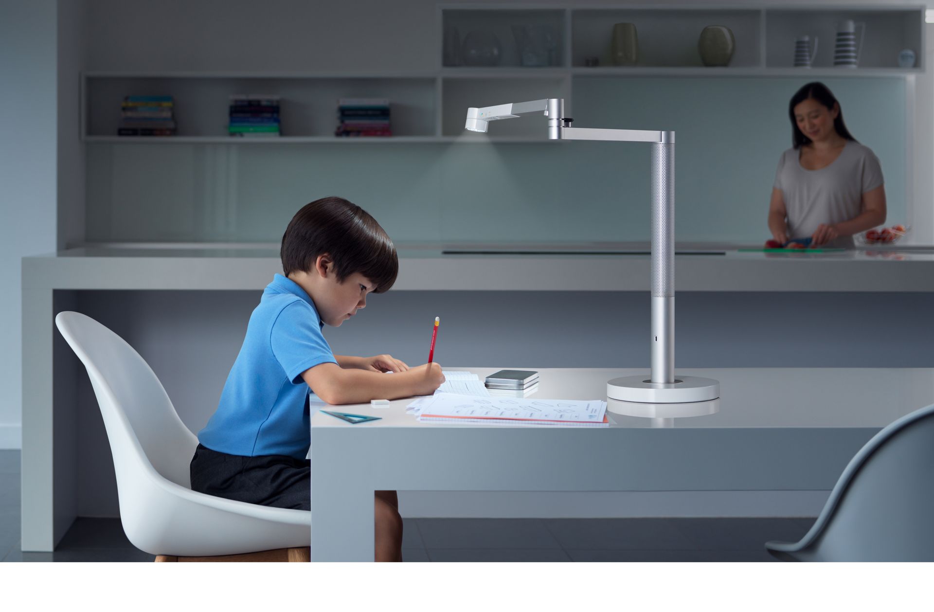 Un garçon étudie sous une lampe de bureau puissante