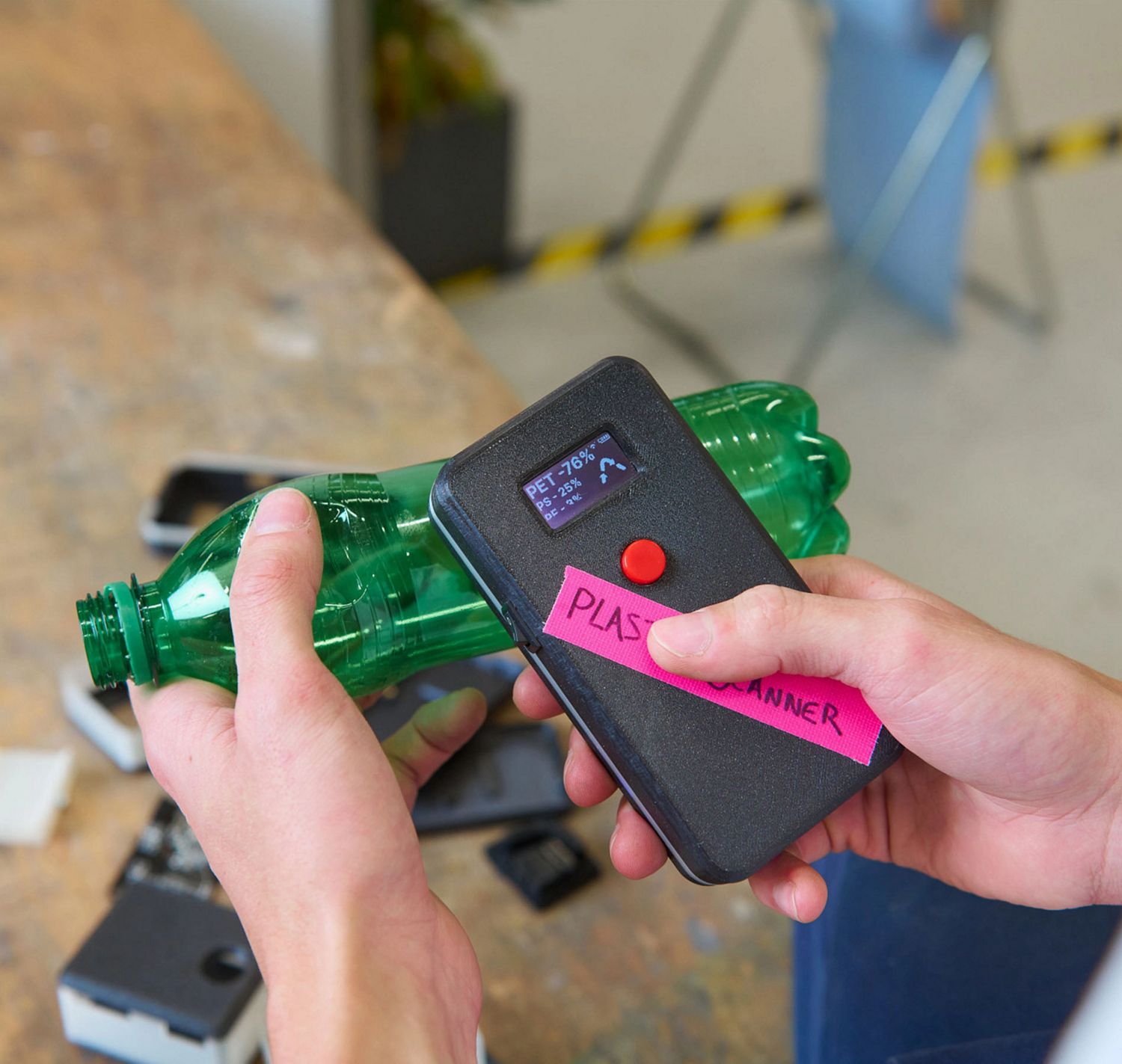 Pair of hands using the Plastic Scanner technology on a green plastic bottle. 