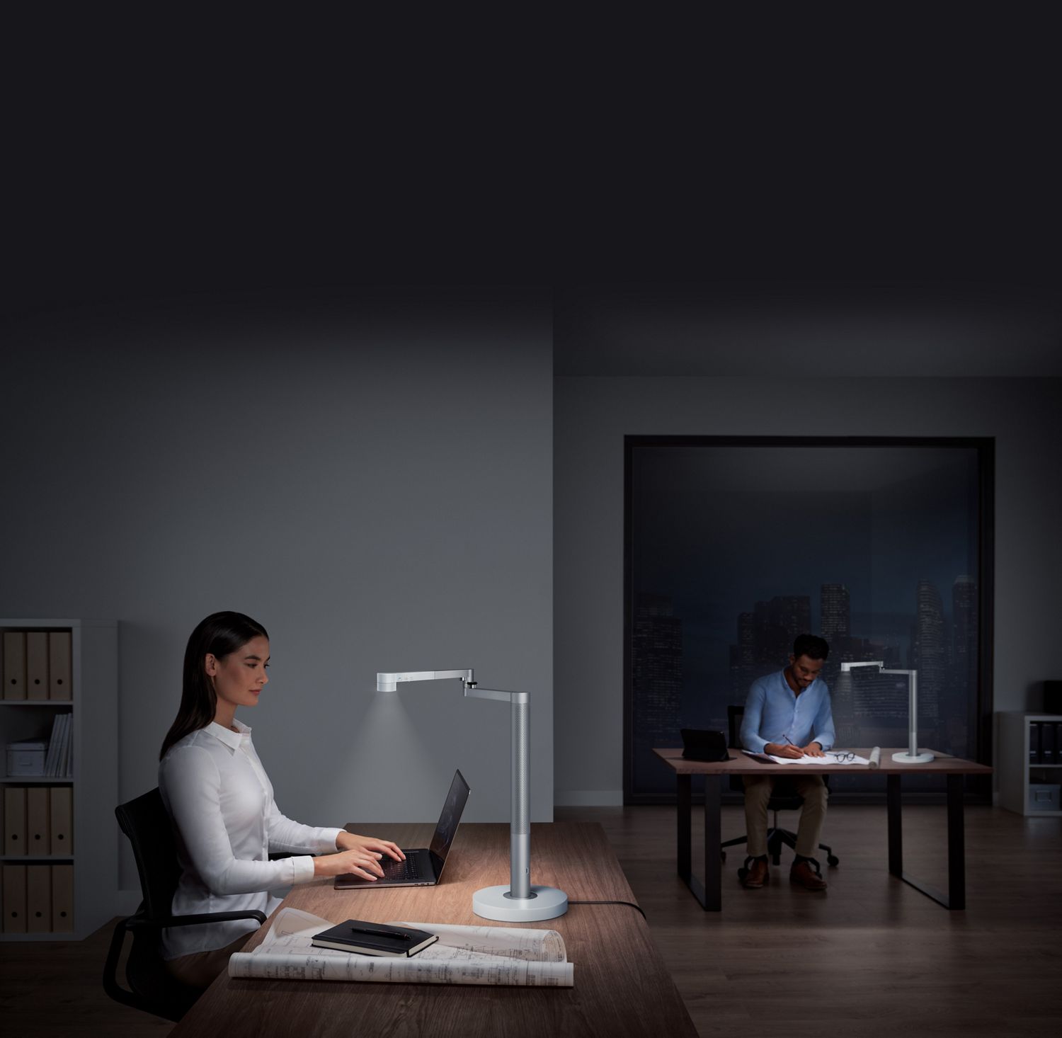 Une femme et un homme travaillent sous une lampe de bureau puissante