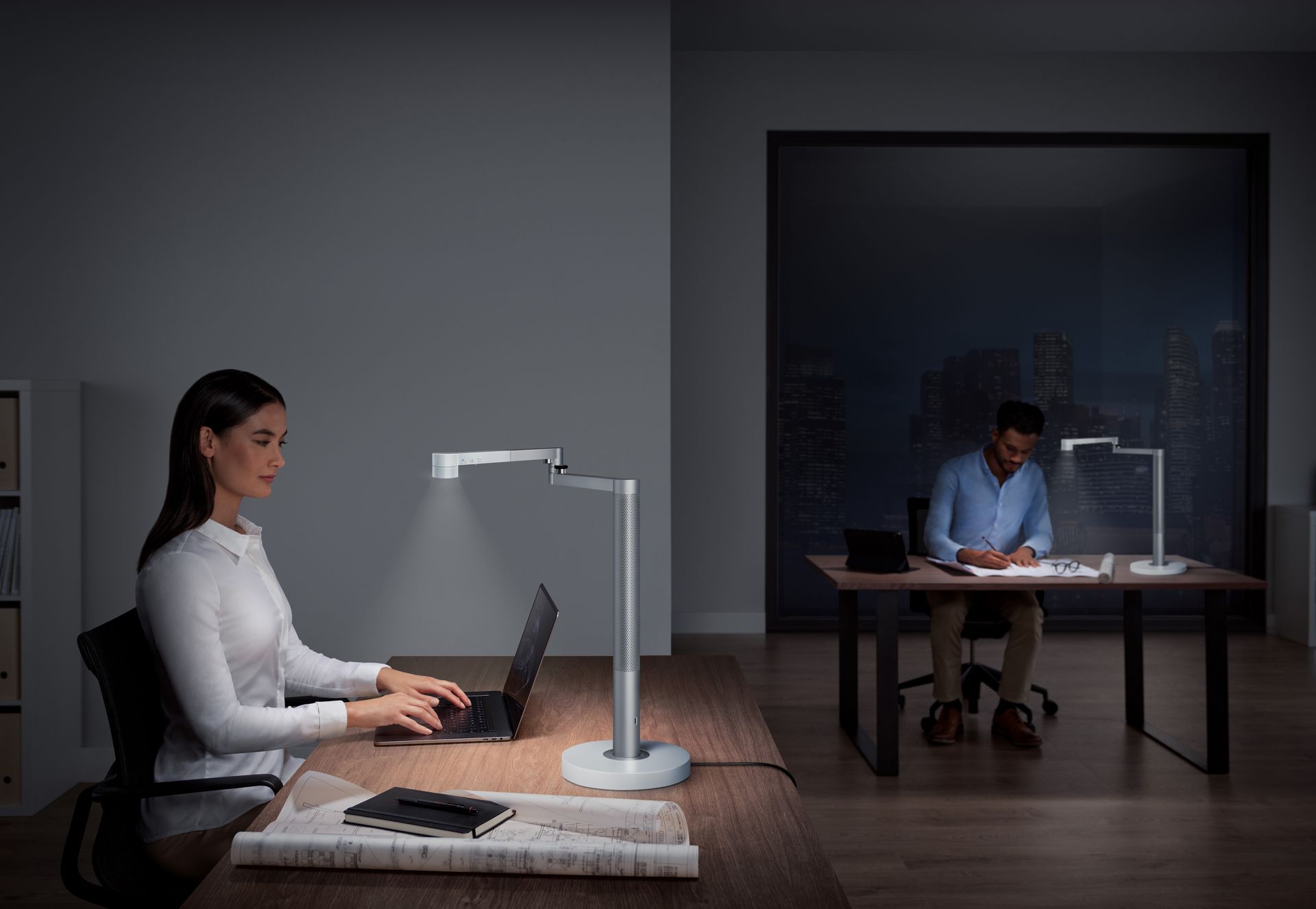 Une femme et un homme travaillent sous une lampe de bureau puissante