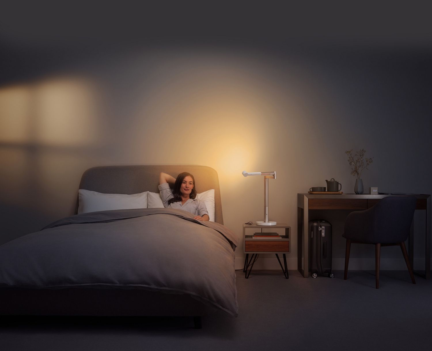 Une femme boit du thé au lit, sous un éclairage relaxant.