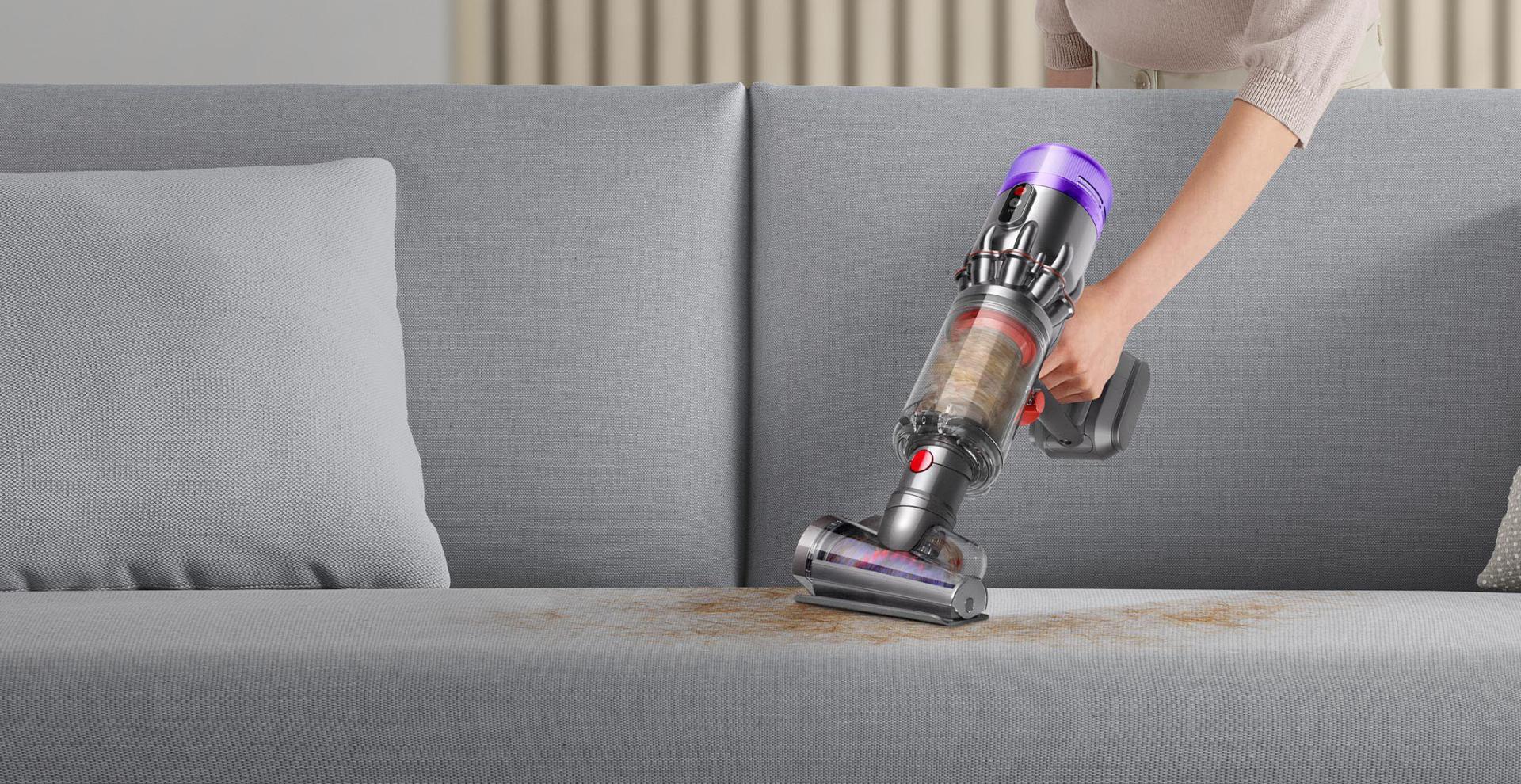 Dyson Humdinger vacuum being used to clean couch