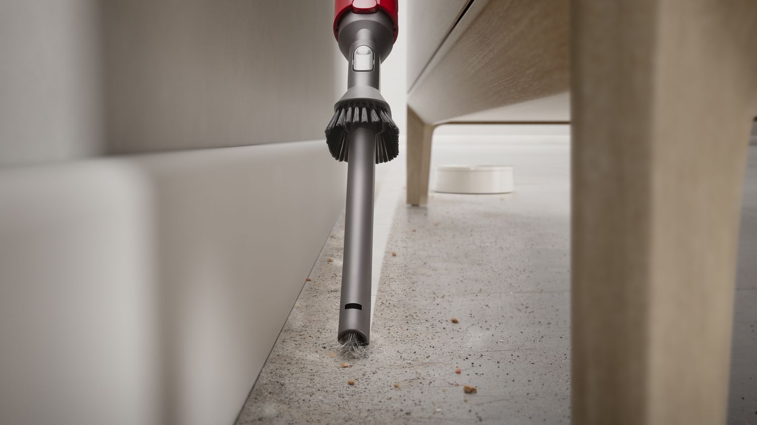 Combination tool cleaning up dirt and debris behind furniture 