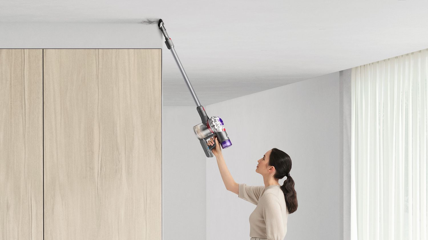 Woman cleanin ceiling with Dyson V7 vacuum