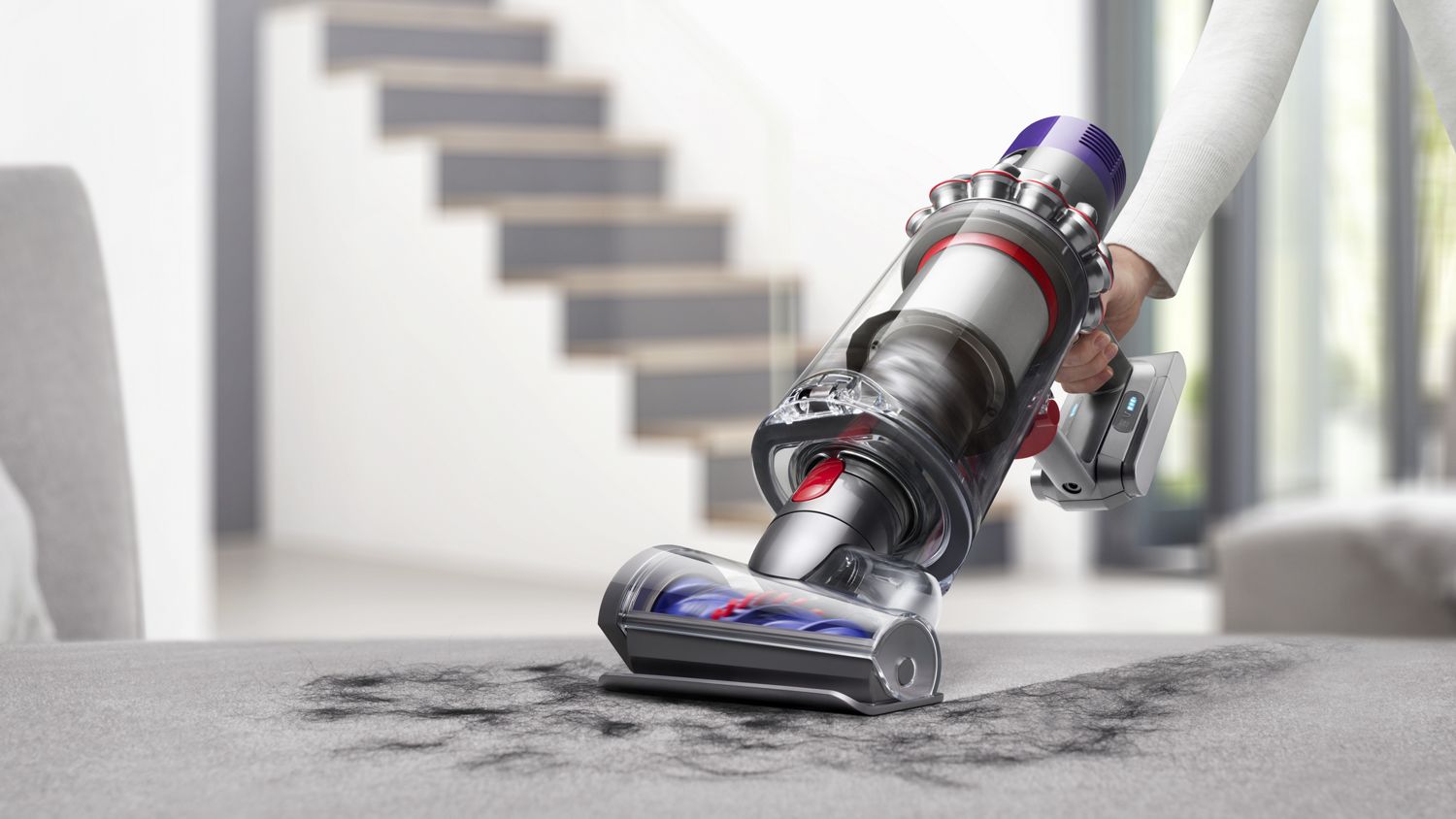 Dyson V10 Animal cordless vacuum in handheld mode picking up debris from carpet.
