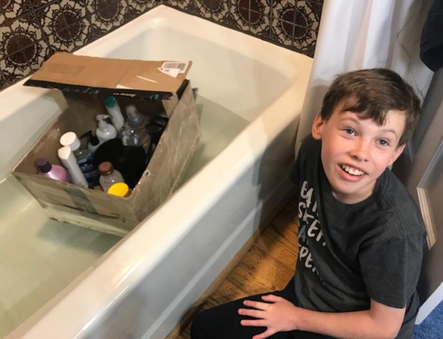 A young engineer shows off his cardboard boat.