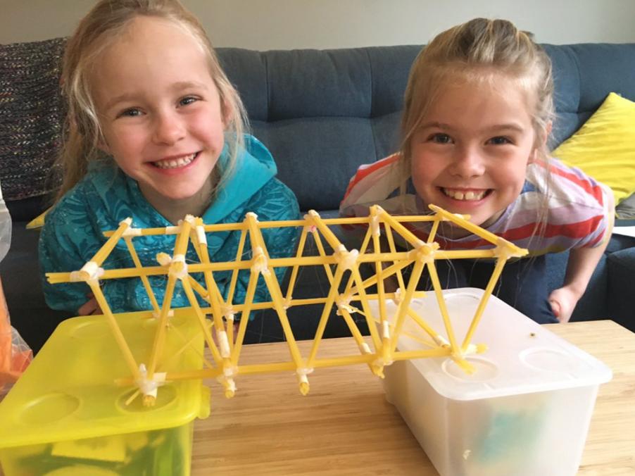 Two young engineers show off their spaghetti bridge.