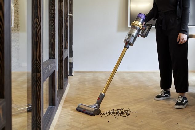 Mann beim Benützen eines kabellosen Dyson-Staubsaugers zur Bodenreinigung