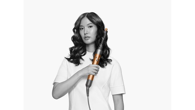 Woman with the Dyson Supersonic hair dryer with the diffuser attachment. 