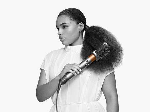 Woman with the Dyson Supersonic hair dryer with the diffuser attachment.