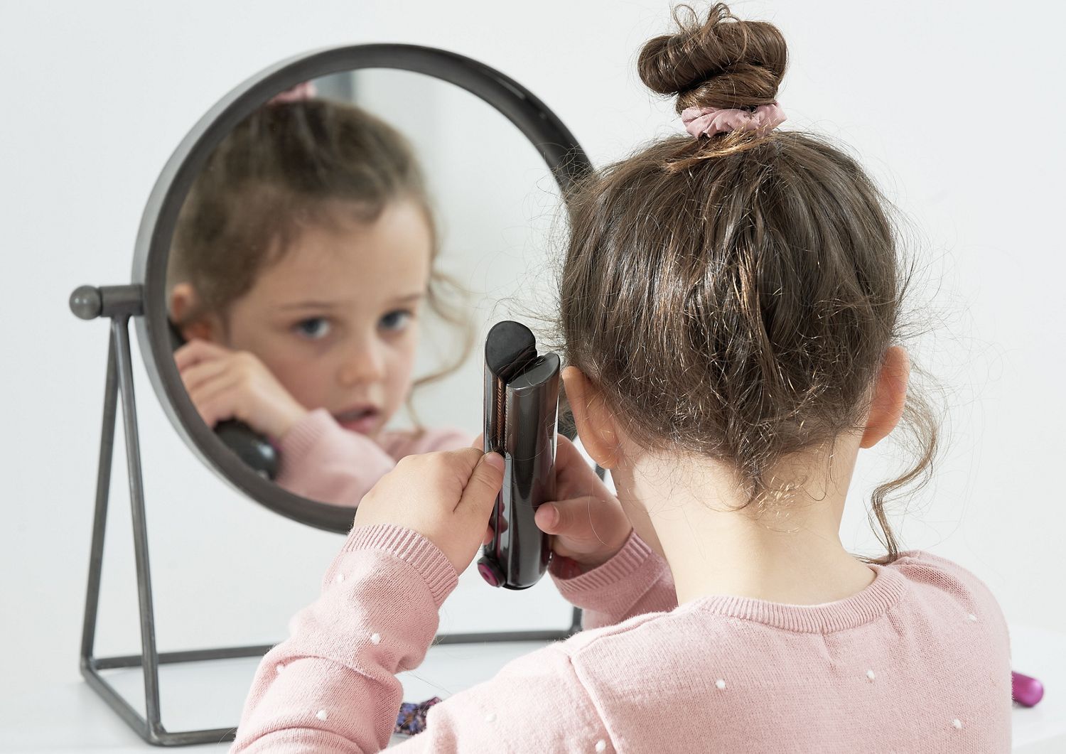 a child using a Dyson Corrale straightener 