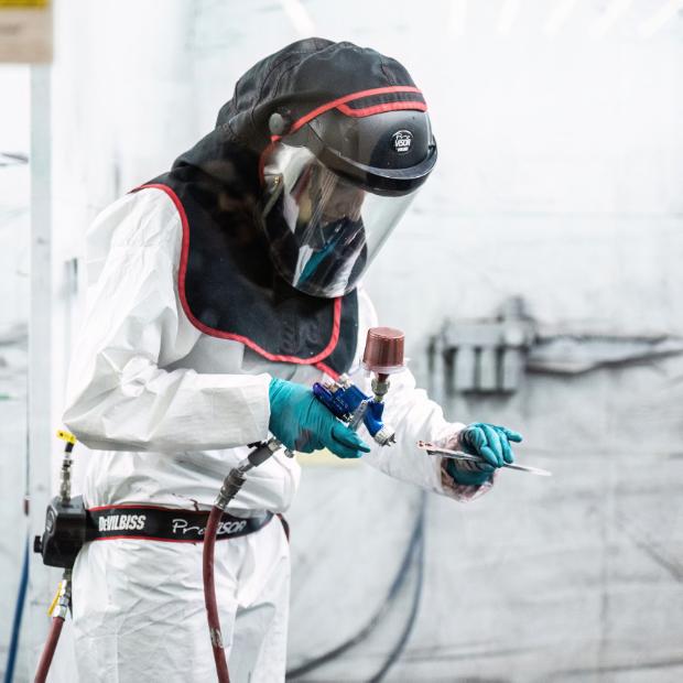 zdjęcie pracownika nakładającego farbę na element